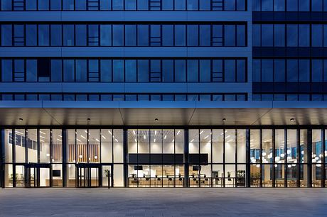 Sleek, modern building with glass walls and a warm, inviting interior space.