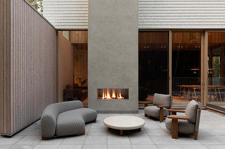 A modern and minimalist living space with a central fireplace, large windows, and sleek furnishings.
