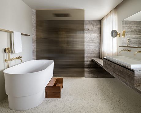 A modern bathroom with a freestanding tub, textured stone walls, and wood accents.