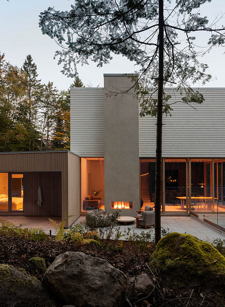 Sleek, modern residence with floor-to-ceiling windows, fireplace, and lush natural surroundings.