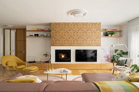 Warm, cozy living room with patterned wallpaper, built-in shelves, and a fireplace.