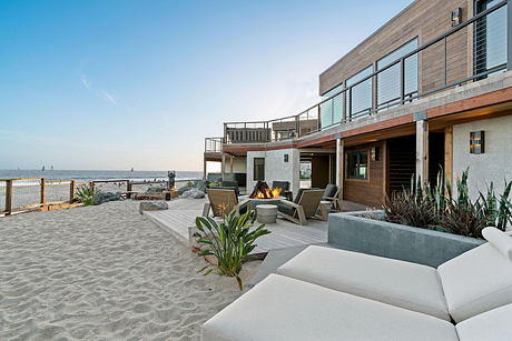 Modern beachfront home with sleek architectural design, balconies, and relaxing outdoor lounge area.