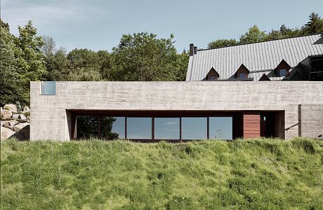 A modern concrete and glass structure nestled in a lush, verdant landscape.