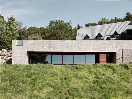 A modern concrete and glass structure nestled in a lush, verdant landscape.