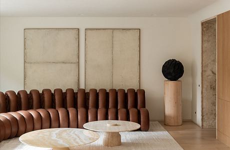 Minimalist living room with leather sofa, wooden accent pieces, and abstract art.