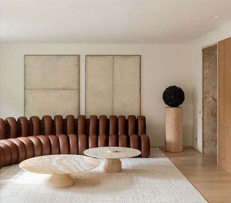 Minimalist living room with leather sofa, wooden accent pieces, and abstract art.