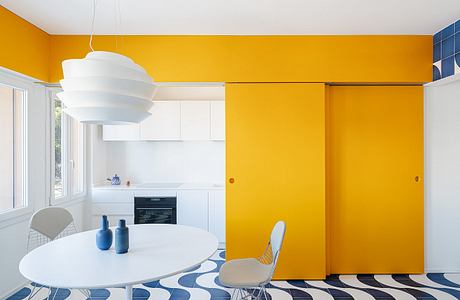 A vibrant yellow and blue color scheme with a modern, minimalist kitchen and dining area.