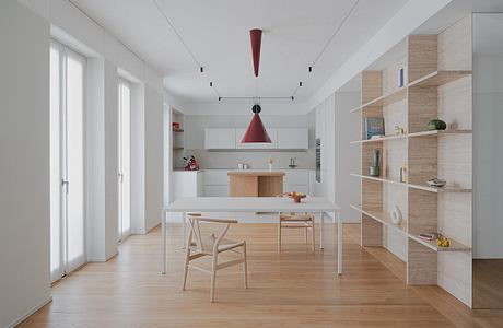 Minimalist kitchen-dining area with a red pendant light and wooden furniture.