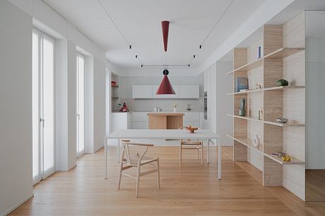 Minimalist kitchen-dining area with a red pendant light and wooden furniture.