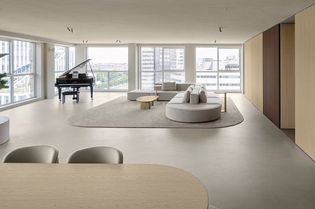 Expansive room with floor-to-ceiling windows, plush seating, and a grand piano. Refined, modern interior design.