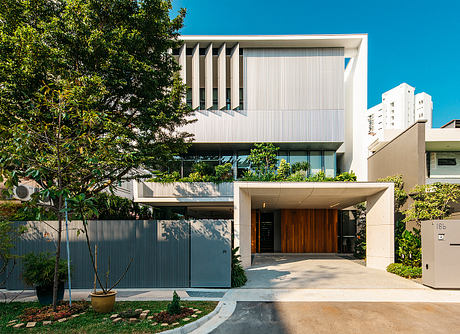 A modern, multi-story building with a striking facade and lush landscaping surrounding the entrance.