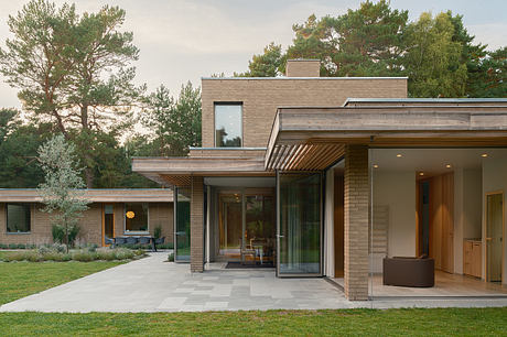 Contemporary home with brick facade, glass walls, and open-plan layout overlooking lush garden.