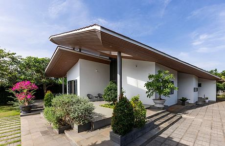 A modern single-story home with a slanted roof, patio, and lush landscaping.