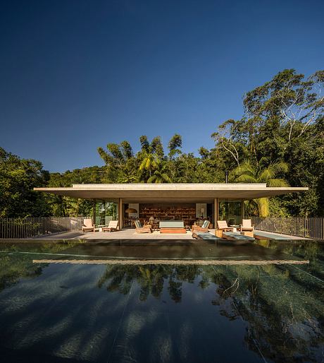 Stunning modern pavilion with floor-to-ceiling glass walls, surrounded by lush tropical greenery.