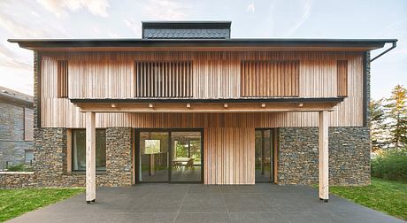 A modern wooden and stone exterior with a wide overhang and large glass windows.