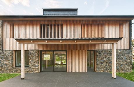 A modern wooden and stone exterior with a wide overhang and large glass windows.