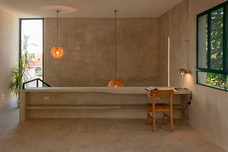 Warm, minimalist interior with concrete walls, wooden desk, and pendant lights.