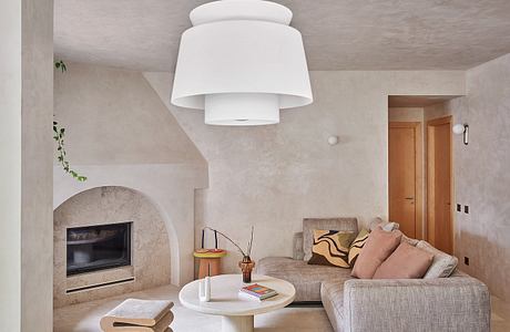 Cozy living room with a fireplace, neutral-toned furnishings, and a statement pendant light.