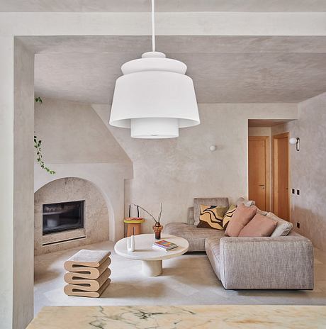 Cozy living room with a fireplace, neutral-toned furnishings, and a statement pendant light.