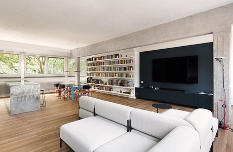 Sleek, modern living space with bookshelves, TV, and large windows overlooking nature.