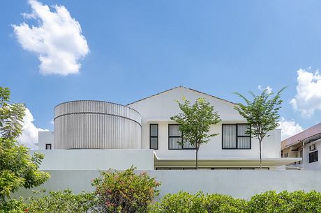 Modern, sleek architectural design with curved walls, large windows, and lush greenery surrounding the building.