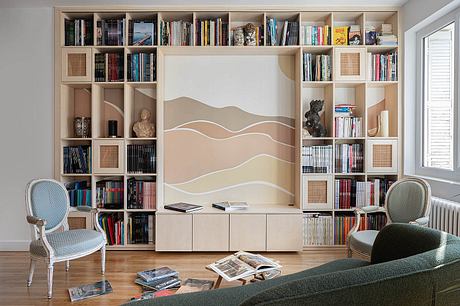 A cozy living room with built-in bookshelves, a patterned wall, and two chairs.