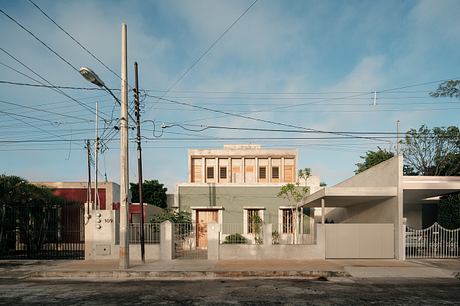 Beige stucco building with decorative shutters and gates, power lines in foreground.