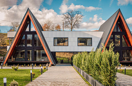 A modern, A-frame building with sleek exterior, glass walls, and landscaped surroundings.