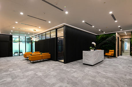 Modern lobby with sleek black partitions, plush orange couches, and a large marble reception desk.