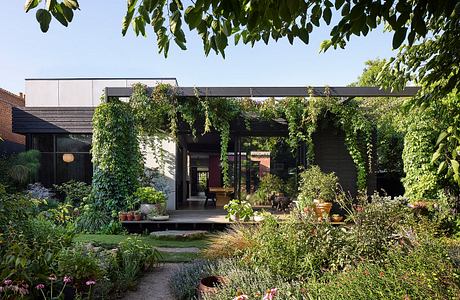 A modern, glass-enclosed structure with a lush, verdant garden surrounding it.