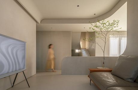 Serene living space with minimalist design, potted tree, and recessed lighting.