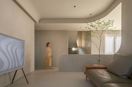 Serene living space with minimalist design, potted tree, and recessed lighting.