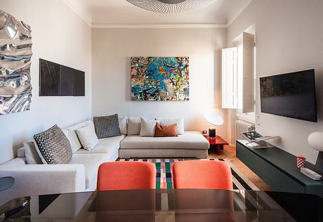 Stylish living room with colorful artwork, sleek furniture, and modern lighting fixtures.