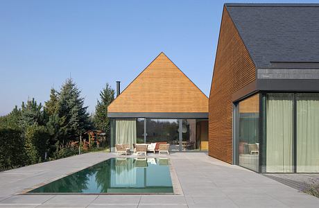 Contemporary home with striking triangular roof, sleek glass walls, and minimal pool.