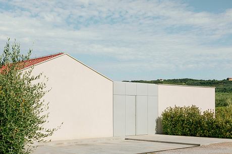 A modern, minimalist building with a flat roof and clean lines, surrounded by greenery.