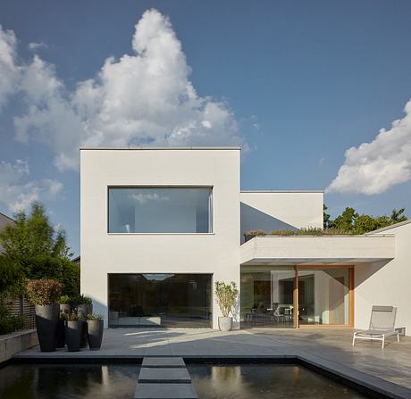 A modern, minimalist house with clean lines, large windows, and an outdoor patio with a pool.