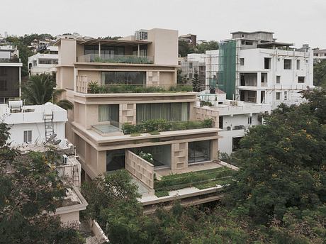 A modern, multi-level residential building with extensive greenery and terraces.