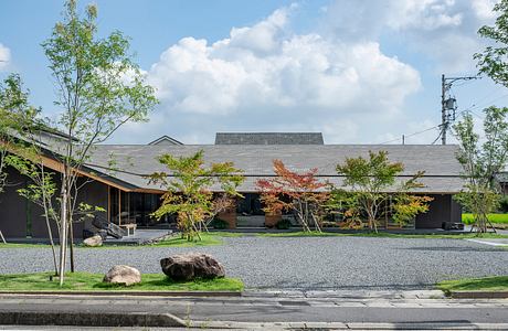 A modern, low-profile building with a generous overhang, surrounded by trees and gravel.