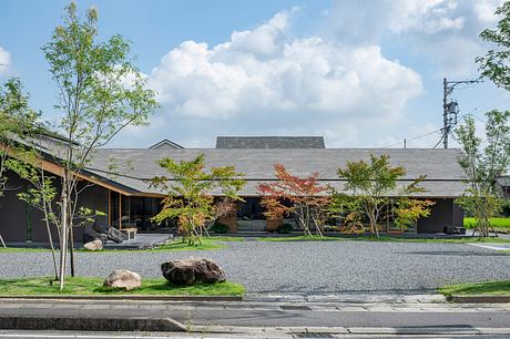 A modern, low-profile building with a generous overhang, surrounded by trees and gravel.