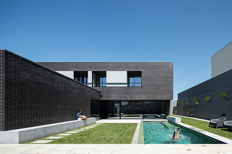 A sleek, modern building with a central courtyard and swimming pool, featuring bold architectural elements and materials.