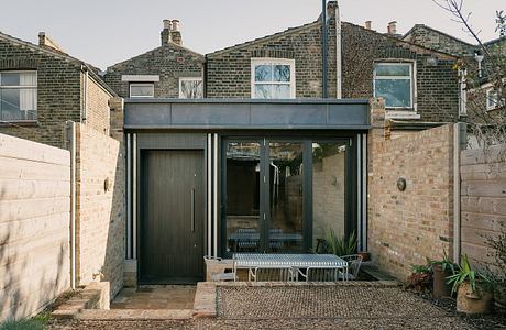 A modern glass and brick extension with a sheltered entrance and seating area.