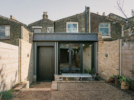 A modern glass and brick extension with a sheltered entrance and seating area.