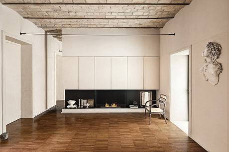 Minimalist living room with exposed brick ceiling, neutral tones, and built-in shelving.