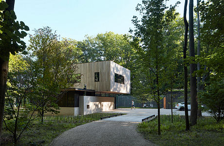 Sleek, modern architecture nestled in a lush, wooded environment with a gravel pathway leading to the entrance.