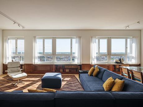 Spacious living room with large windows offering sweeping city views and modern furniture.