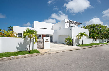 A modern tropical villa with clean white walls, palm trees, and architectural details.