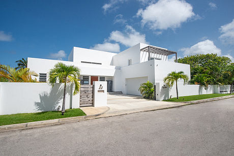 A modern tropical villa with clean white walls, palm trees, and architectural details.