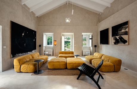 A spacious living room with a vaulted ceiling, plush yellow sofas, and modern artwork.