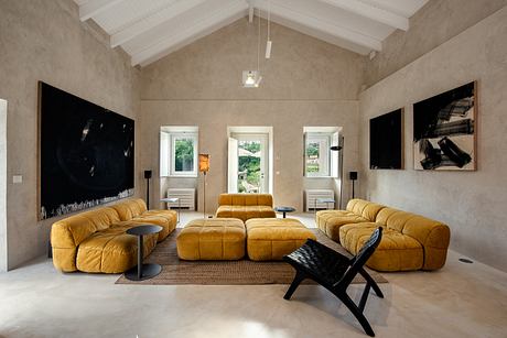 A spacious living room with a vaulted ceiling, plush yellow sofas, and modern artwork.