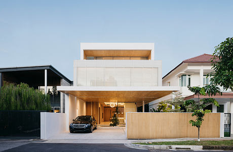 Modern two-story home with wooden accents, glass façade, and a parked vehicle in the driveway.